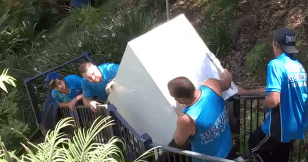 Team carrying fridge up stairs